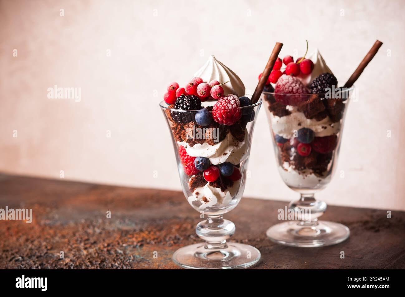 Schokoladenbrownies, frische Beeren, Baiser und Schlagsahne in Gläsern. Köstliches Dessert im Sommer. Stockfoto