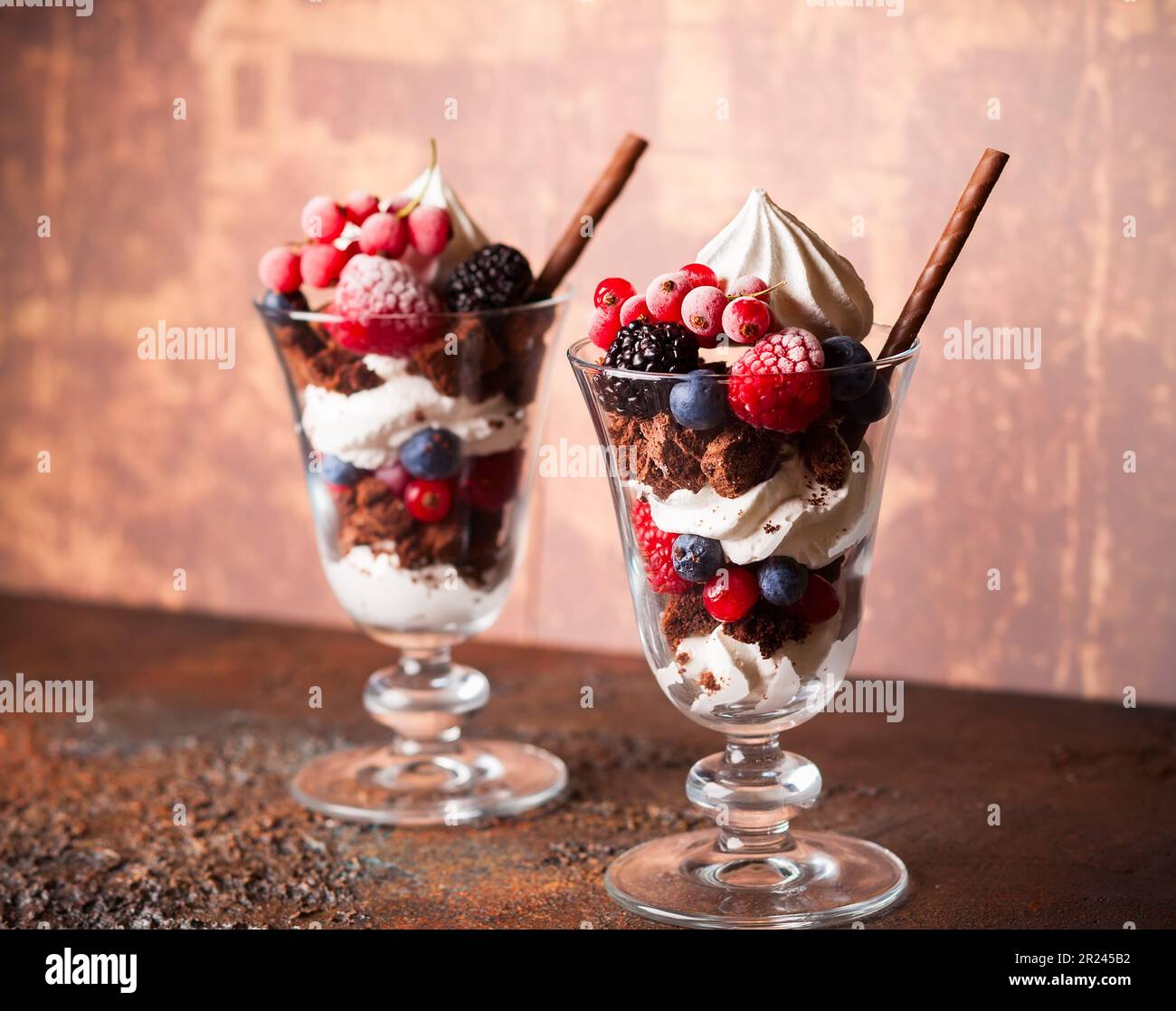 Schokoladenbrownies, frische Beeren, Baiser und Schlagsahne in Gläsern. Köstliches Dessert im Sommer. Stockfoto