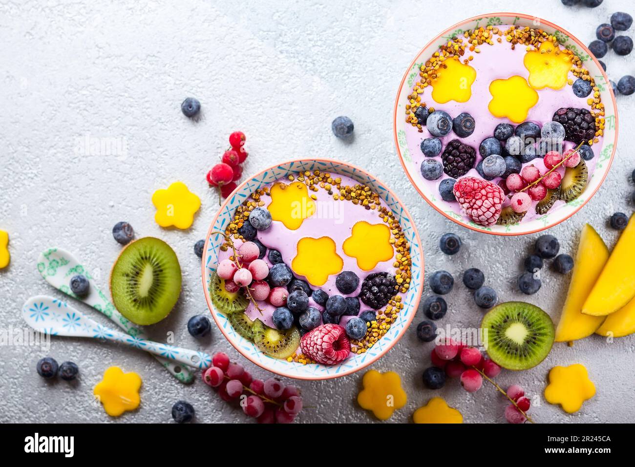 Smoothie in Schüsseln für ein gesundes Frühstück. Beerenjoghurt mit Heidelbeeren, Himbeeren, Brombeeren, roten Johannisbeeren, Mango, Kiwi und Bienenpollen Stockfoto