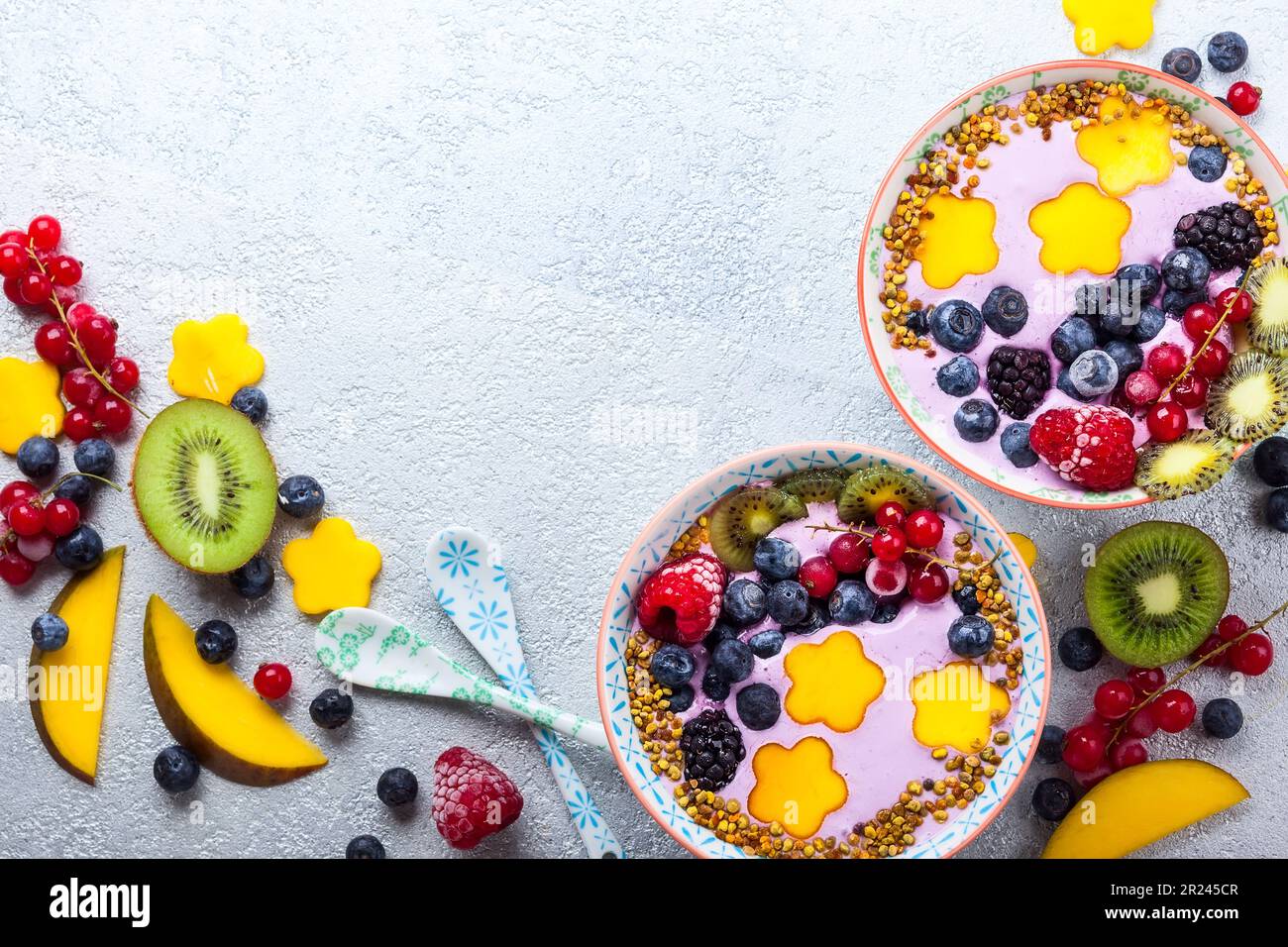 Smoothie in Schüsseln für ein gesundes Frühstück. Beerenjoghurt mit Heidelbeeren, Himbeeren, Brombeeren, roten Johannisbeeren, Mango, Kiwi und Bienenpollen Stockfoto