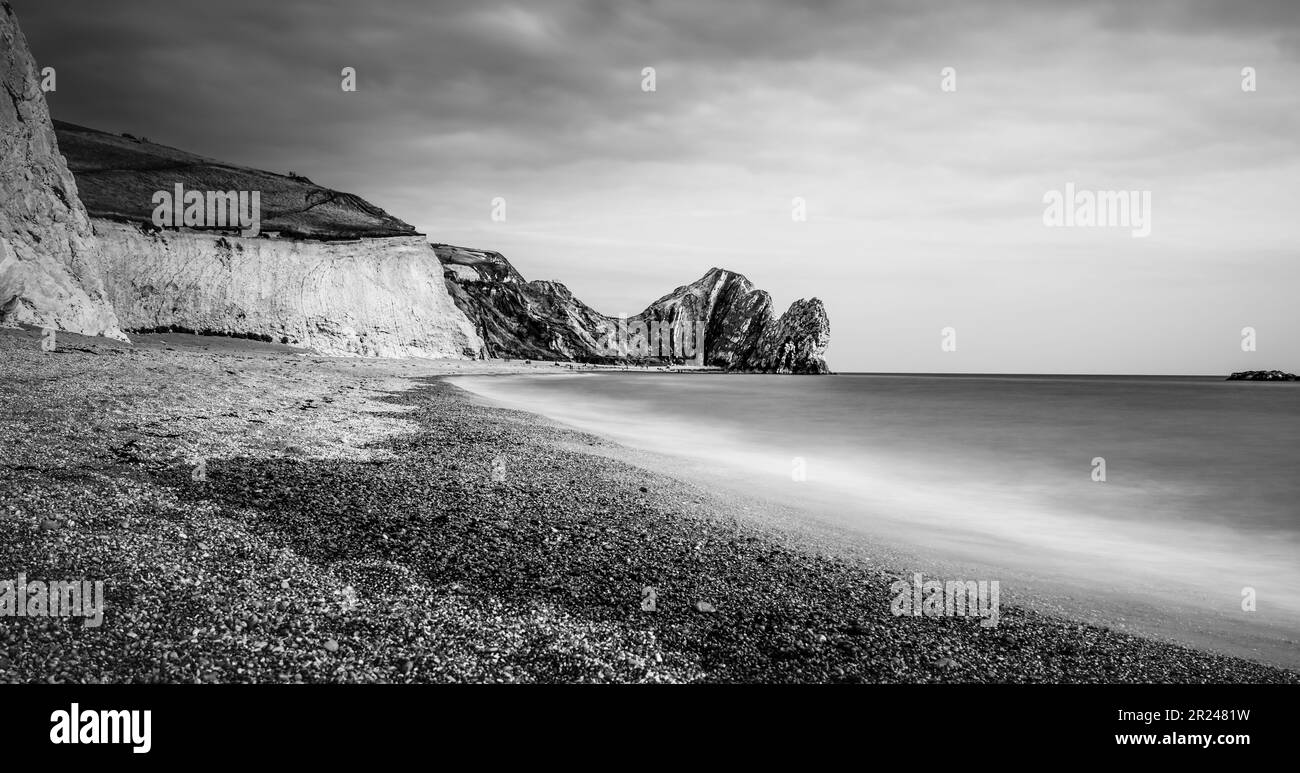 Eine atemberaubende Schwarz-Weiß-Aufnahme eines Strands am Rand einer dramatischen Klippe in England Stockfoto