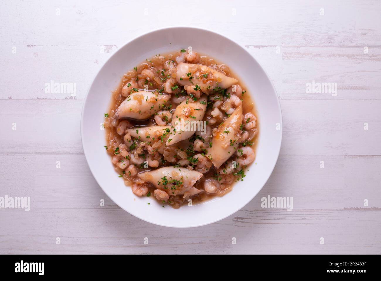 Baby-Tintenfisch-Eintopf mit Kartoffeln und Garnelen. Traditionelles spanisches Rezept. Stockfoto