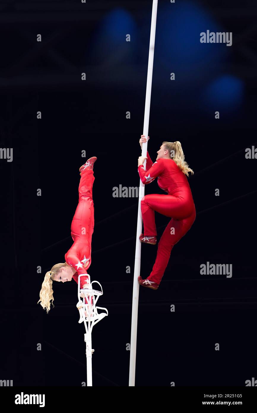 Der elegante Acrobat Performer steht und klettert Einen Pol in Einem Zirkus über Einer Bühne hinauf Stockfoto