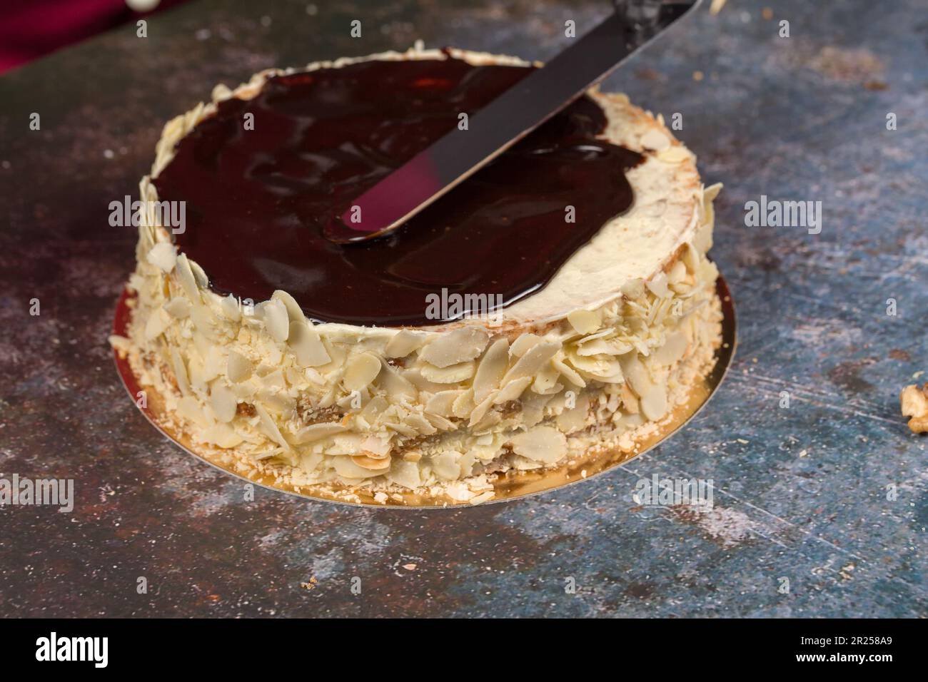 Esterhazy-Kuchen. Kuchendekoration. Schokoladenglasur. Vom Küchenchef dekorierter Kuchen. Der Konditor schmiert flüssige Schokoladenglasur. Hausgemachtes Backkonzept Stockfoto