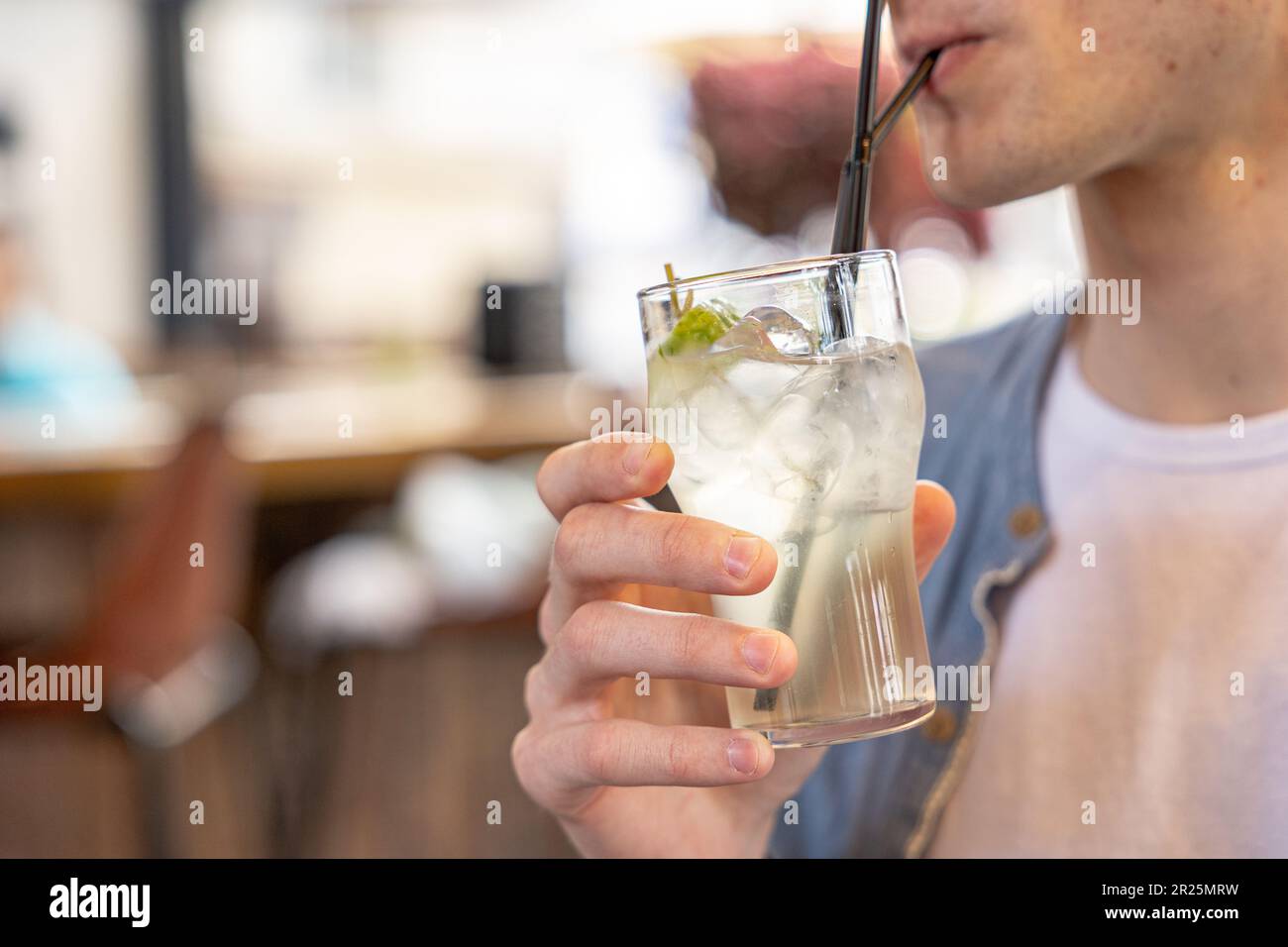 Der Mann trinkt Limonade oder Kokosschwanz durch einen Strohhalm aus Glas mit Eis. Stockfoto