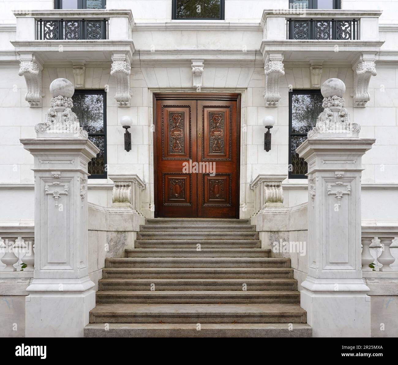 Eingang zum Appartementgebäude mit langer Treppe und eleganter Eingangstür aus geschnitztem Holz Stockfoto