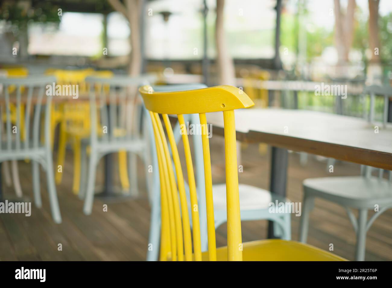 Nahaufnahme von Holzstühlen in einer Bar. Selektiver Fokus auf eine gelbe Nahaufnahme des Stuhls. Balkenansicht, Fokusunschärfe, Idee zur Balkendekoration oder Foto für den Innenbereich Stockfoto