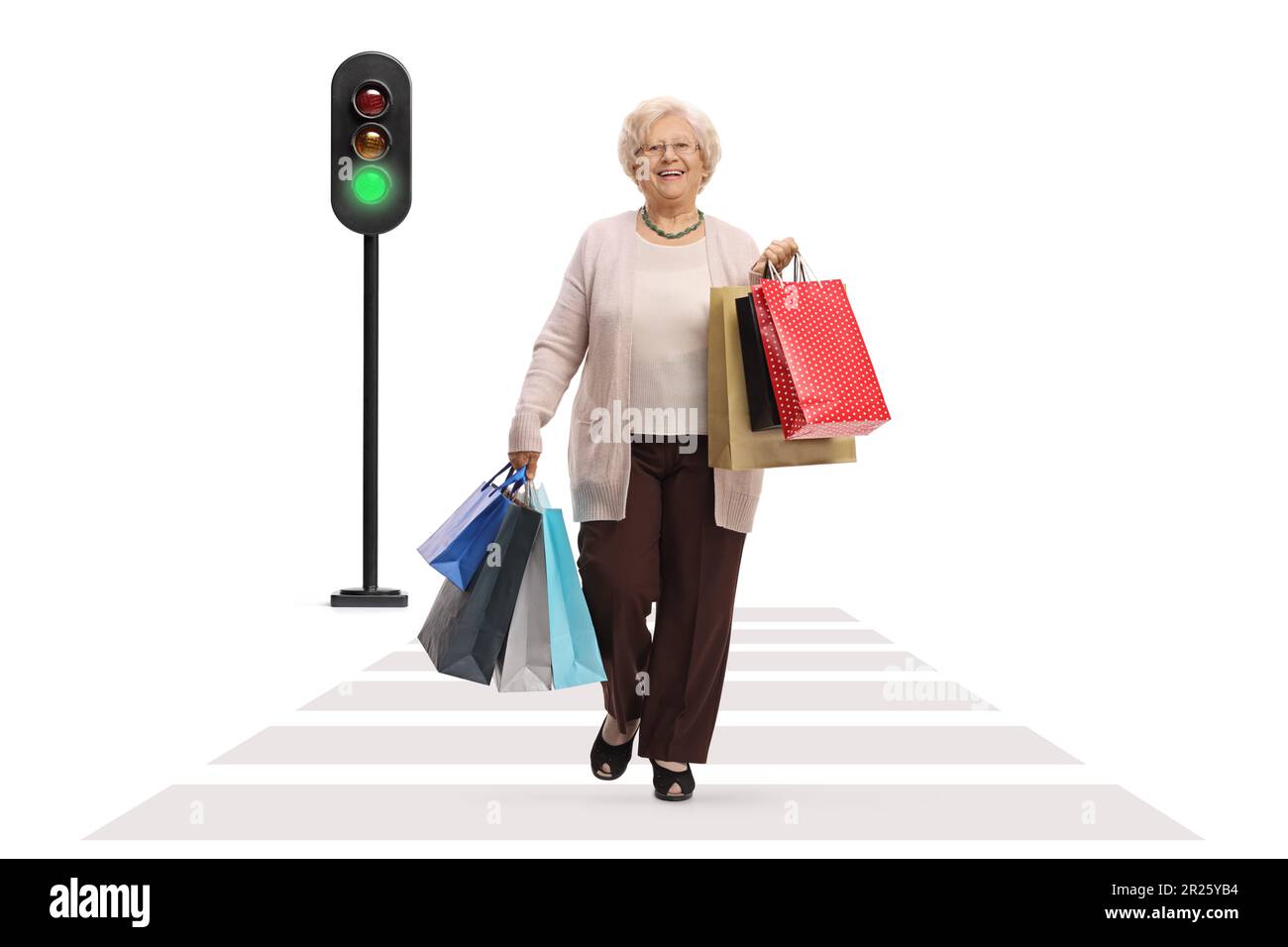 Ein langes Porträt einer glücklichen, reifen Frau mit Einkaufstaschen, die auf einem Fußgängerübergang auf weißem Hintergrund unterwegs ist Stockfoto