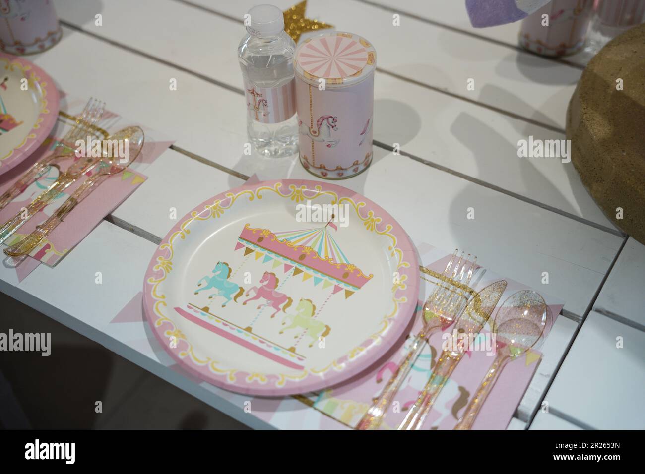 Pferdekarussell für Kinder oder Partytisch mit Karneval-Motiven mit Plastiktellern und Süßigkeiten. Festliche Dekoration für die Geburtstagsparty eines kleinen Mädchens mit Lunch Ta Stockfoto