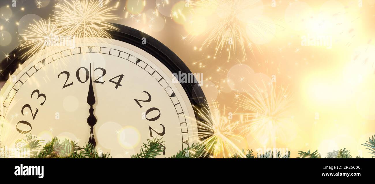 Wechsel von 2023 auf 2024 Uhr Silvester mit magischem Feuerwerk im Hintergrund. Stockfoto