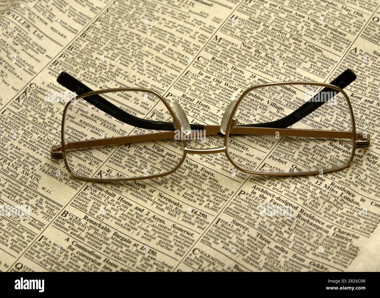 Eine Lesebrille oder eine Brille auf einer alten Zeitung mit sehr kleinem Aufdruck; Lesemodell Stockfoto