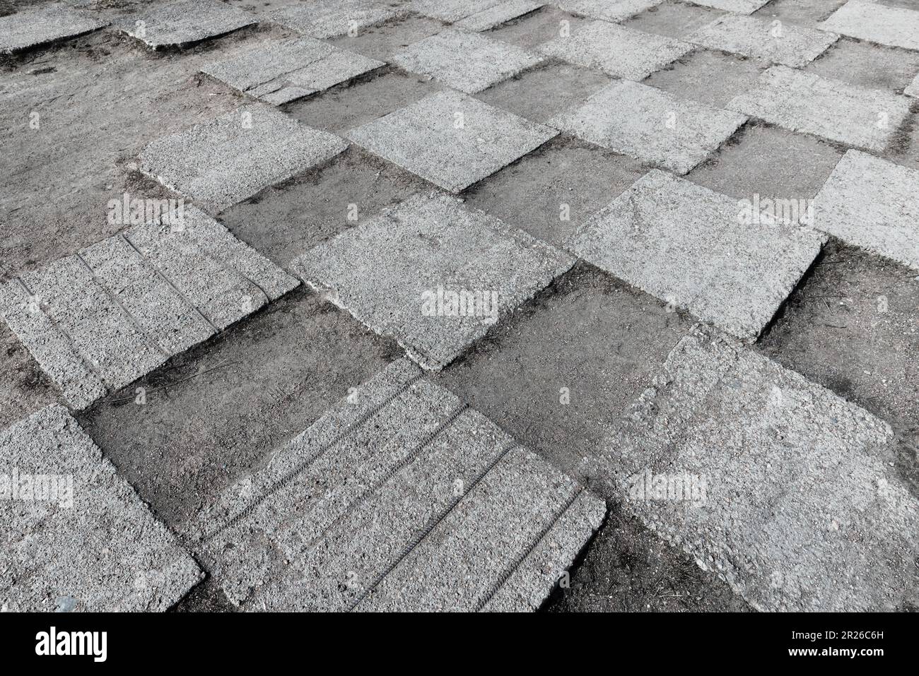 Grunglige Betonfliesen eines städtischen Gehwegs lagen auf einem grauen, staubigen Boden mit Schachbrettmuster, abstraktes Hintergrundbild Stockfoto