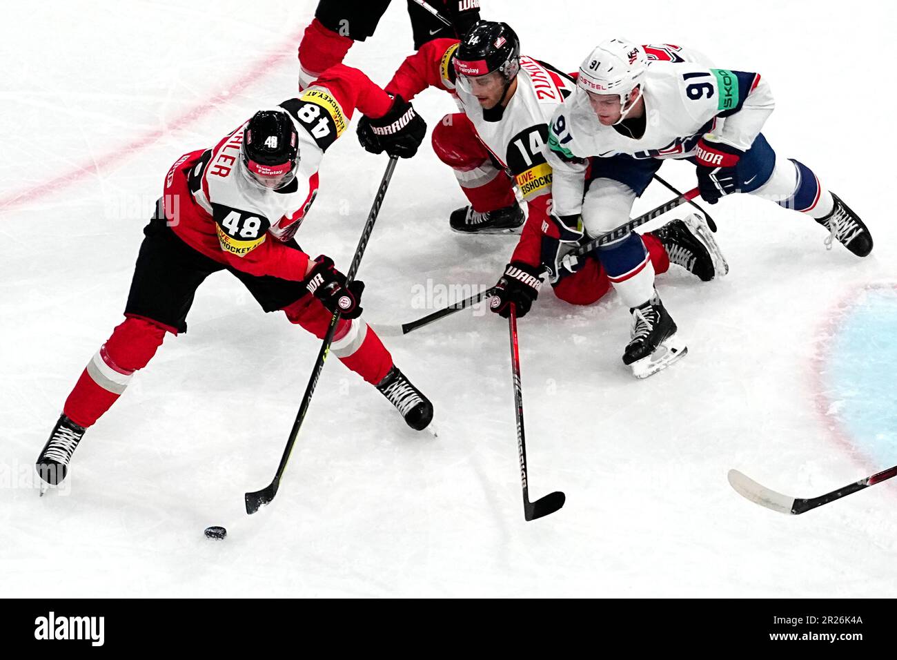 United States Carter Mazur, right, battles for the puck with Austria's Kilian Zundel, centre, and Lucas Thaler during the group A match between United States and Austria at the ice hockey world championship in Tampere, Finland, Wednesday, May 17, 2023. (AP Photo/Pavel Golovkin) Stockfoto