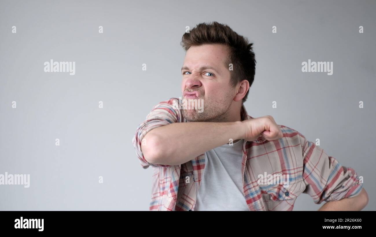 Der junge europäische Mann verhält sich aggressiv, schikaniert ein wütendes Gesicht und bedroht jemanden Stockfoto