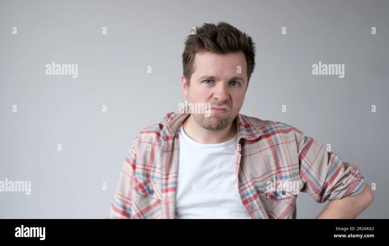 Der junge europäische Mann verhält sich aggressiv, schikaniert ein wütendes Gesicht und bedroht jemanden. Studioaufnahme Stockfoto