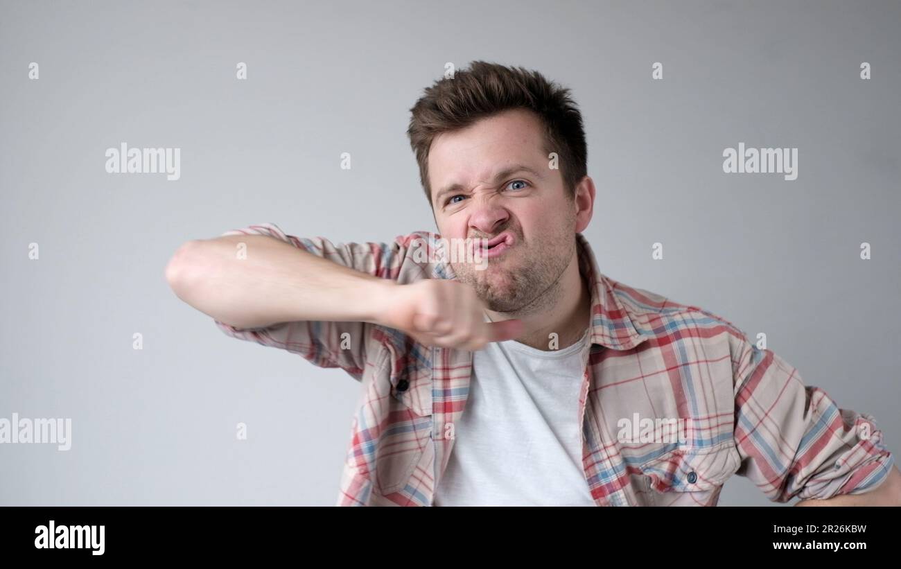 Der junge europäische Mann verhält sich aggressiv, schikaniert ein wütendes Gesicht und bedroht jemanden Stockfoto