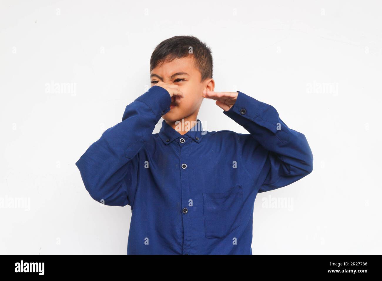Ein Kind, das seine Nase hält und einen schlechten Geruch riecht, isoliert auf Weiß Stockfoto