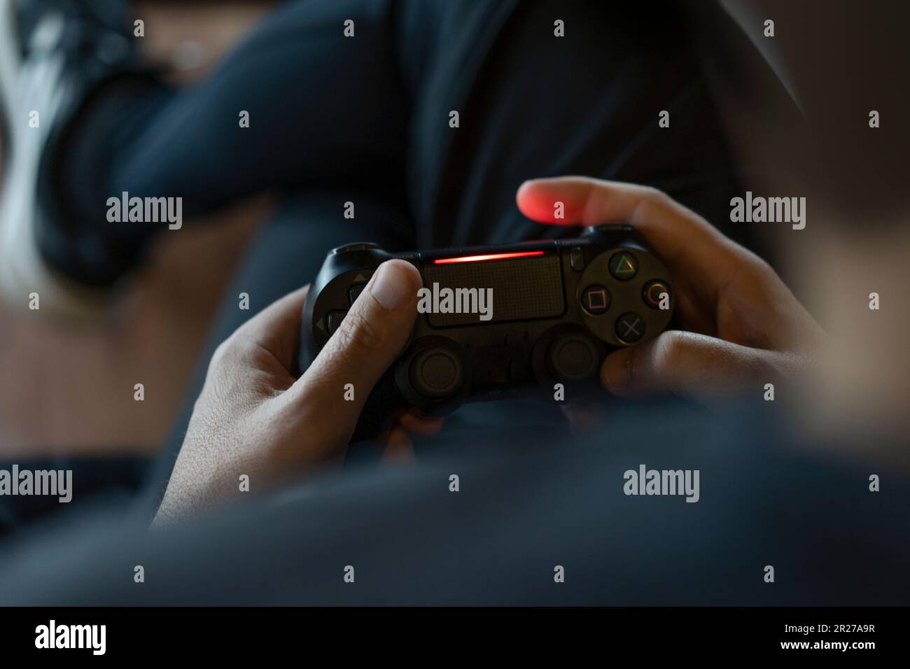 Nahaufnahme der Hände eines erwachsenen Mannes, der einen Joystick hält, während er ein Videospiel auf einer Konsole spielt. Stockfoto