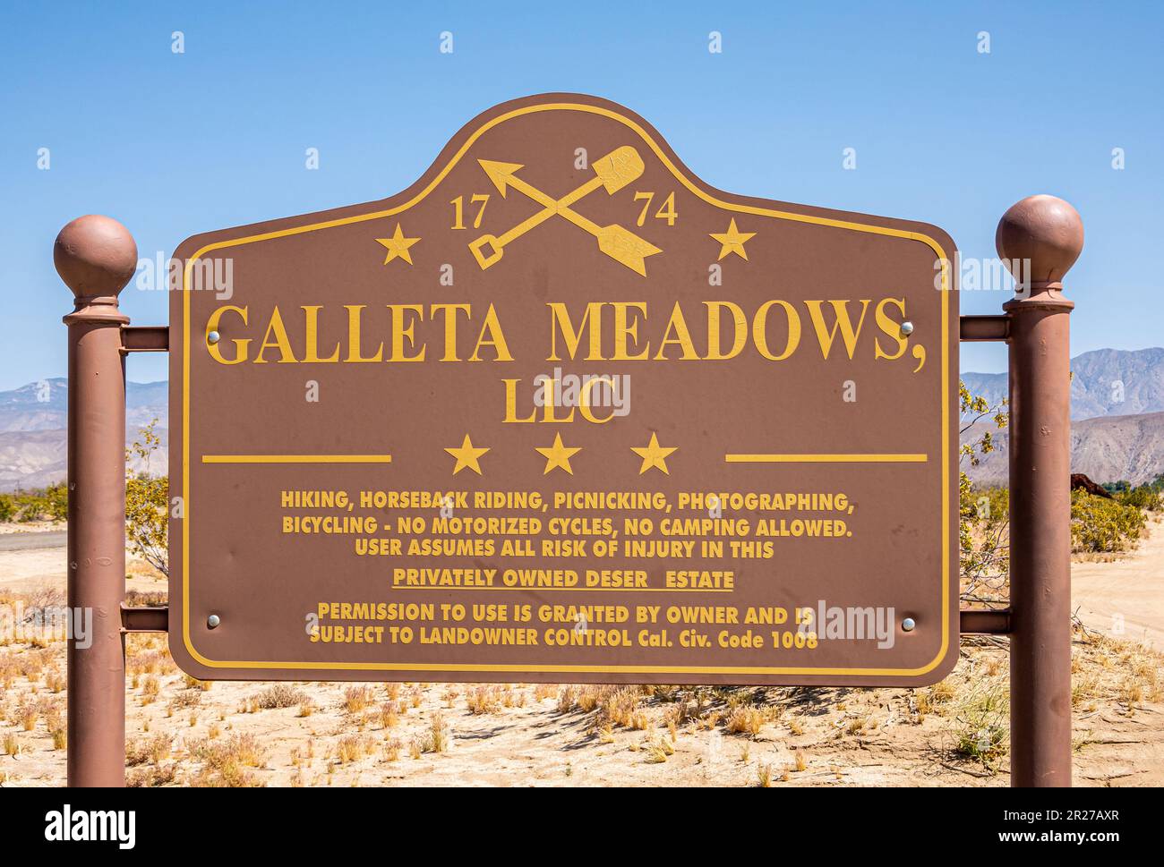 Borrego Springs, CA, USA - 24. April 2023: Galleta Meadows LLC-Schild, gelbe Buchstaben auf braunem Hintergrund, in Wüstenlandschaft entlang der Straße unter Blau Stockfoto