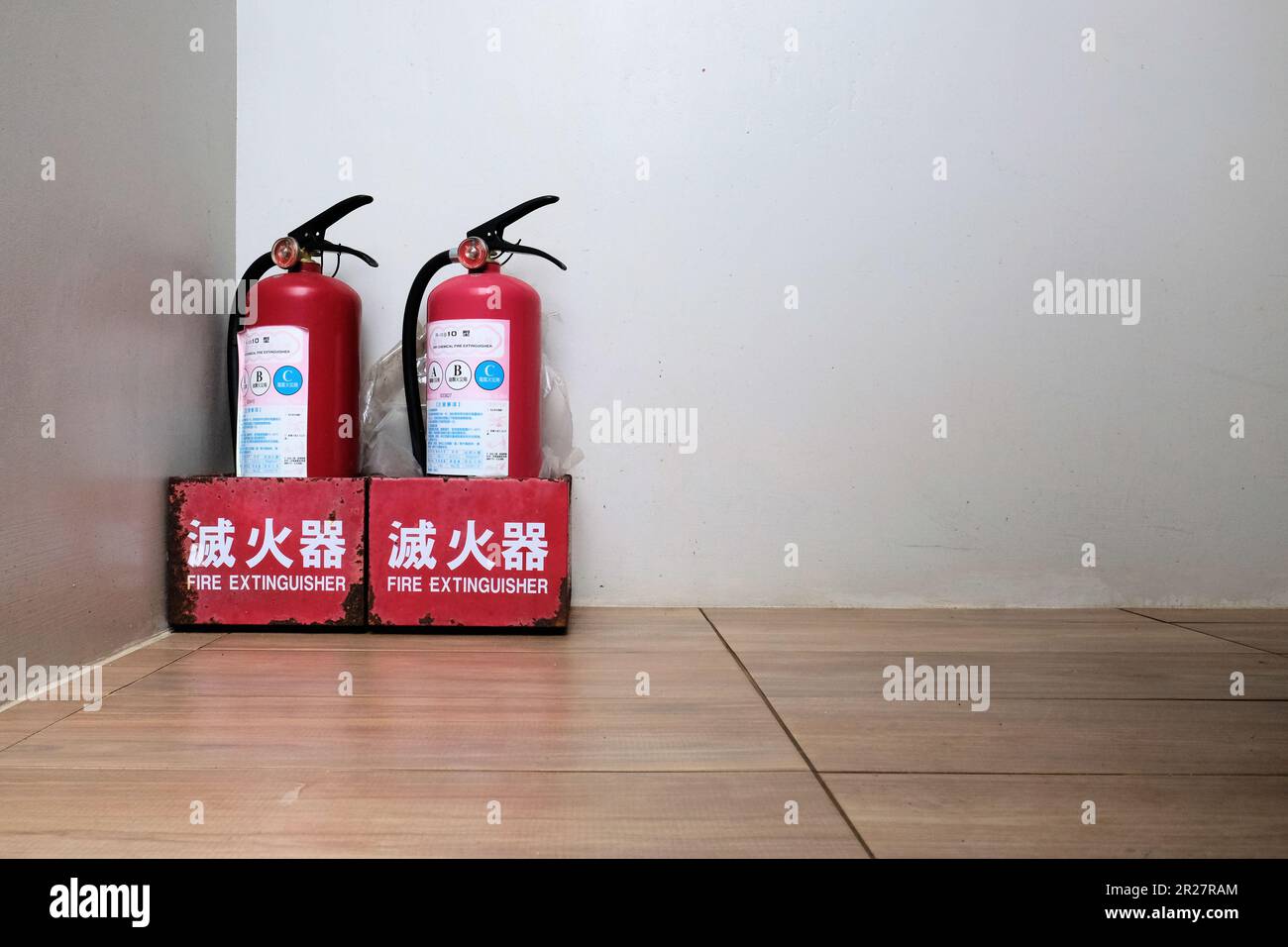 Zwei chemische Trockenfeuerlöscher auf dem Boden in einem Hotelgebäude in Taiwan; chinesische und englische Übersetzung. Stockfoto