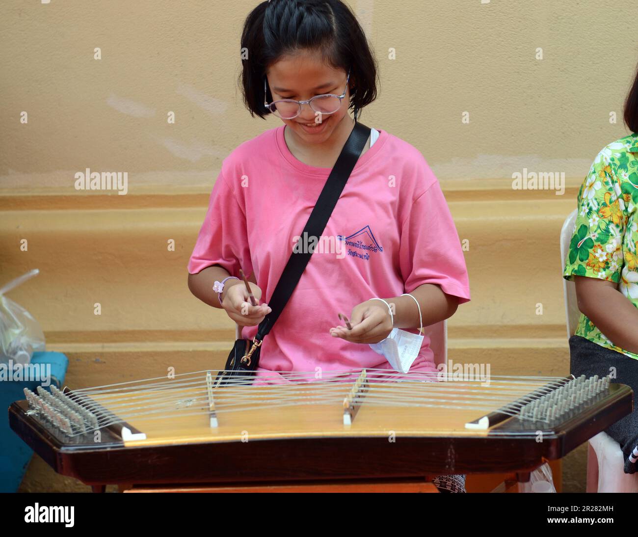Ein thailändisches Mädchen, das das Instrument Khim spielt. Stockfoto