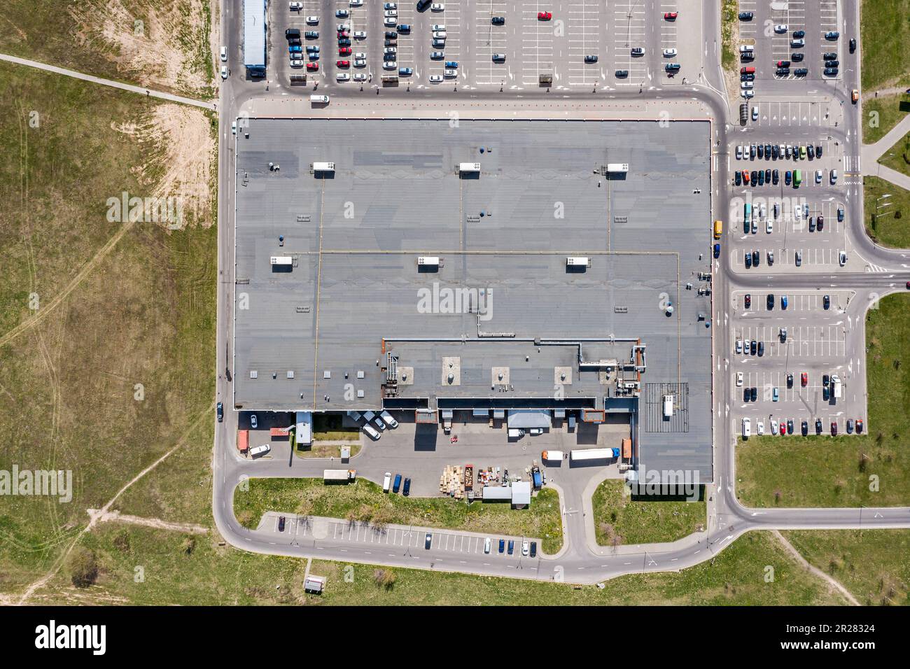 Kieseldach des Einkaufszentrums mit Lüftungsanlagen und Parkplatz mit geparkten Autos. Draufsicht. Stockfoto