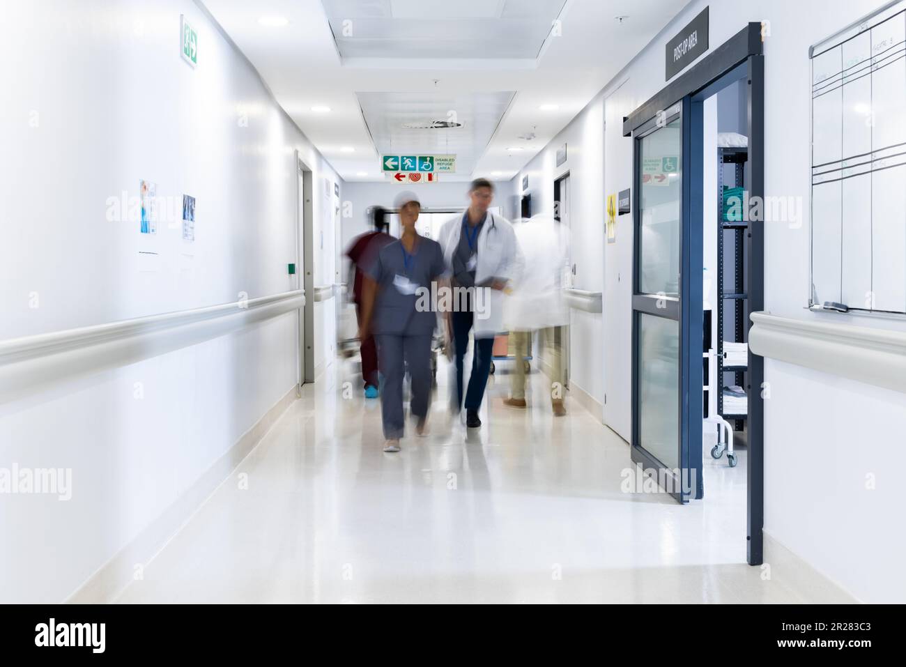 Verschwommene Bewegung von verschiedenen Ärzten und medizinischem Personal im belebten Krankenhausflur, Kopierraum Stockfoto