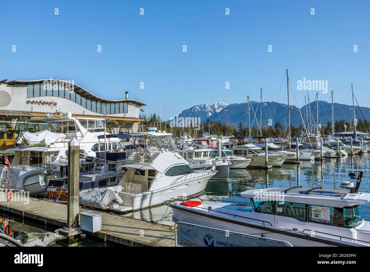 Vancouver, Kanada - März 18,2023: Unter einem sonnigen Himmel in Vancouver, begeistert die Coal Harbour Marina mit ihrem malerischen Blick auf die sanft schwankenden Boote Stockfoto