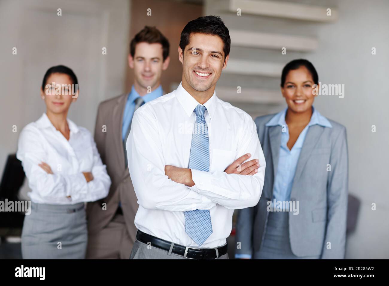 Junger Geschäftsführer mit seinem Team. Ein junger Geschäftsführer, der vor seinem Team steht und selbstbewusst lächelt. Stockfoto