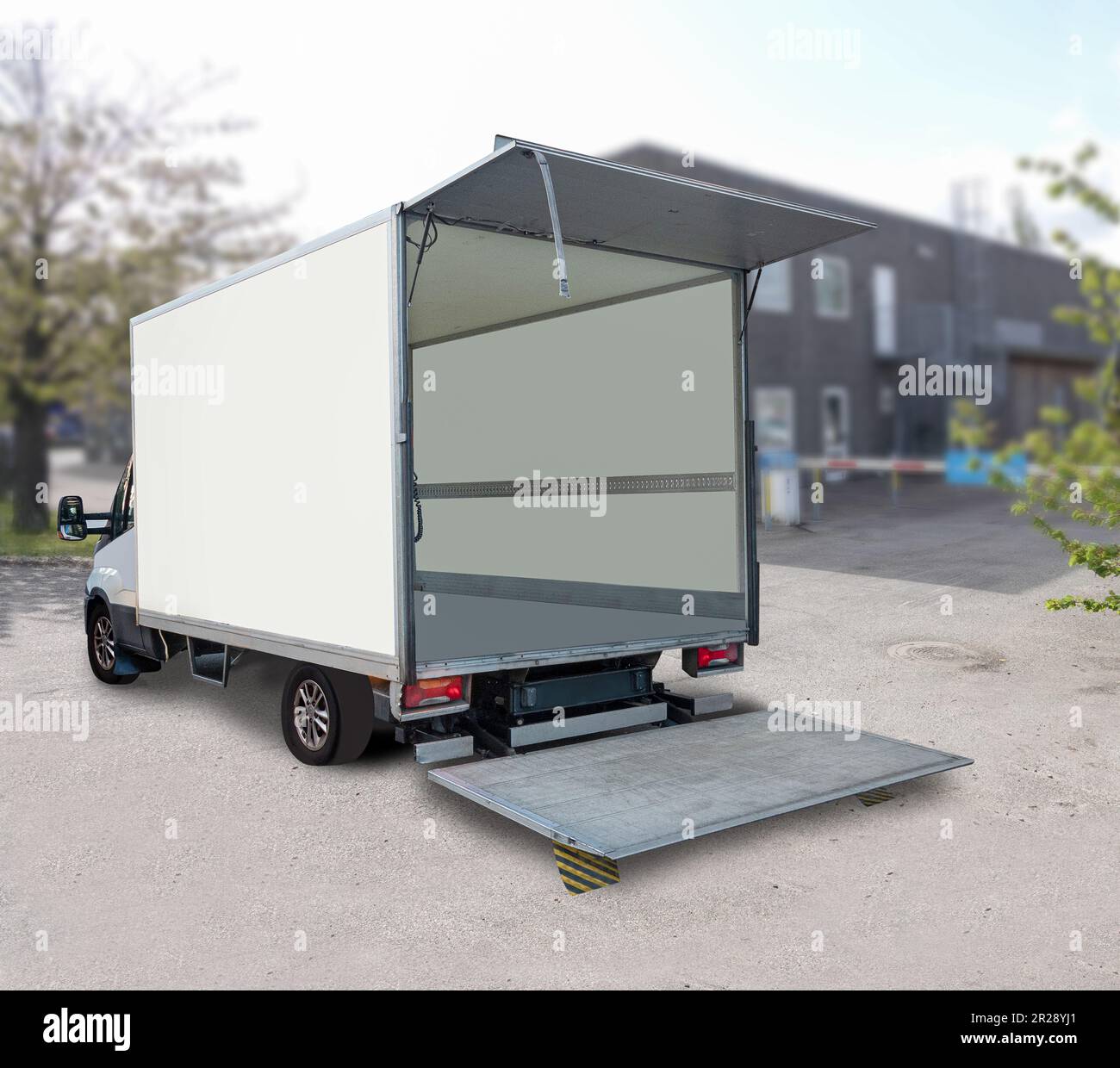 Leerer weißer Lieferwagen mit offener Heckklappe vor dem Geschäftsgebäude. Stockfoto