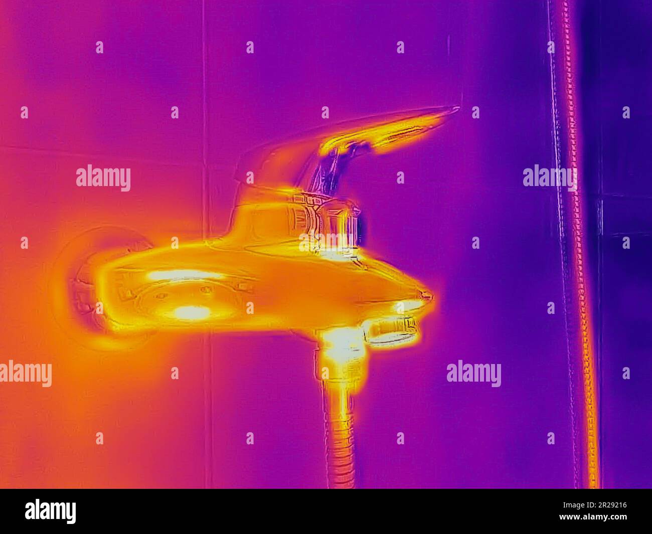 Ein Wärmebild eines Duschhahns, das mit einer Infrarot-Wärmebildkamera aufgenommen wurde und verschiedene Temperaturen und Rohre hinter der Wand zeigt Stockfoto