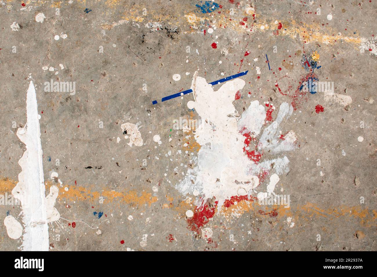 Der Boden ist mit mehreren Tropfen in verschiedenen Farben befleckt. Tropfende Farbe auf dem Betonboden wunderschöne Kunst. Tröpfchen mit roten, schwarzen und weißen Flecken Stockfoto