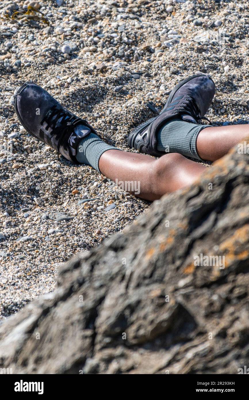 Die Beine eines Walkers, der am Strand des Little Fistral in Newquay in Cornwall in Großbritannien ruht. Stockfoto