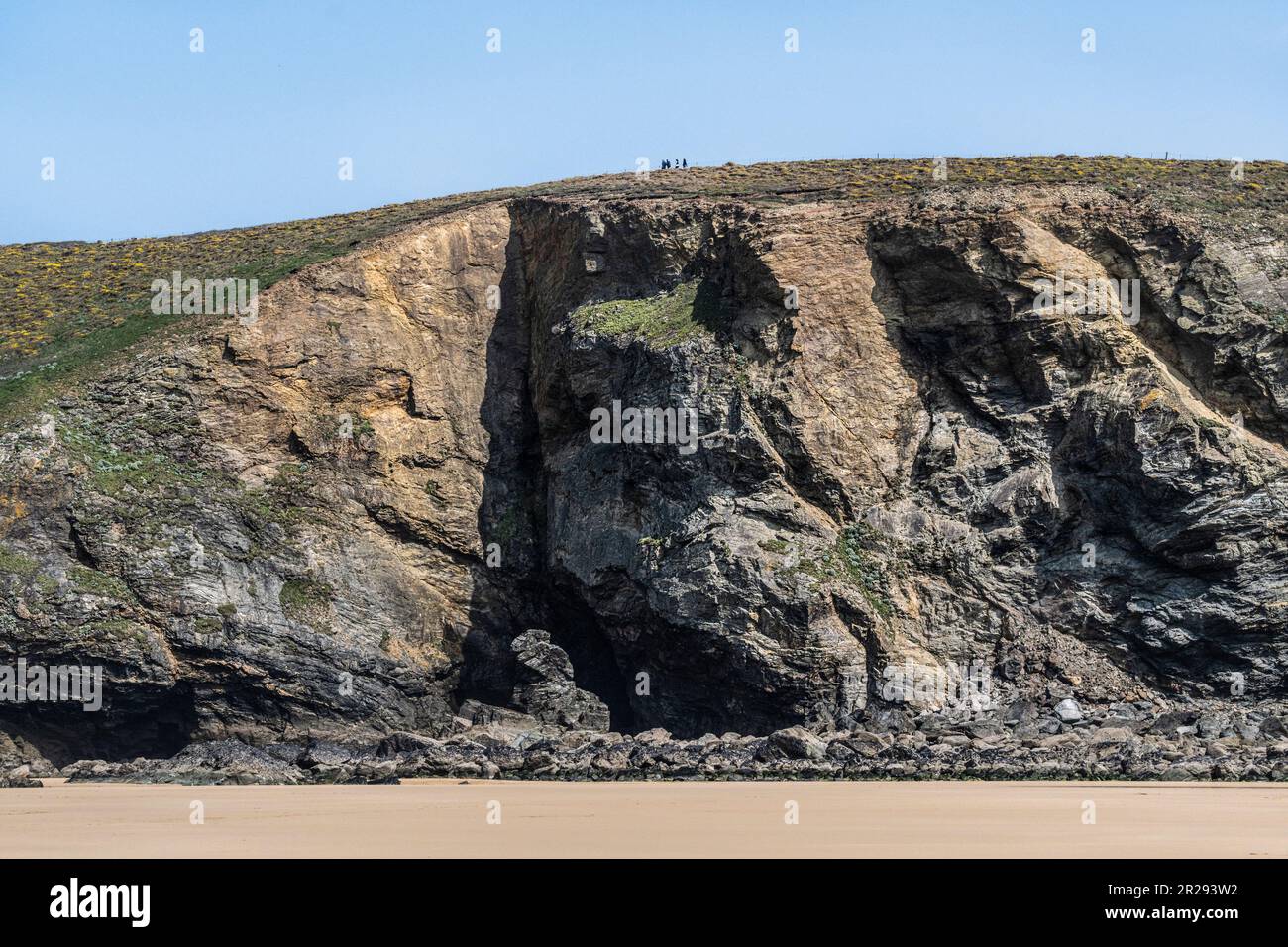 Die winzigen Figuren von Wanderer, die über den majestätischen Klippen mit Blick auf den Strand von Mawgan Porth in Cornwall, Großbritannien, wandern. Stockfoto