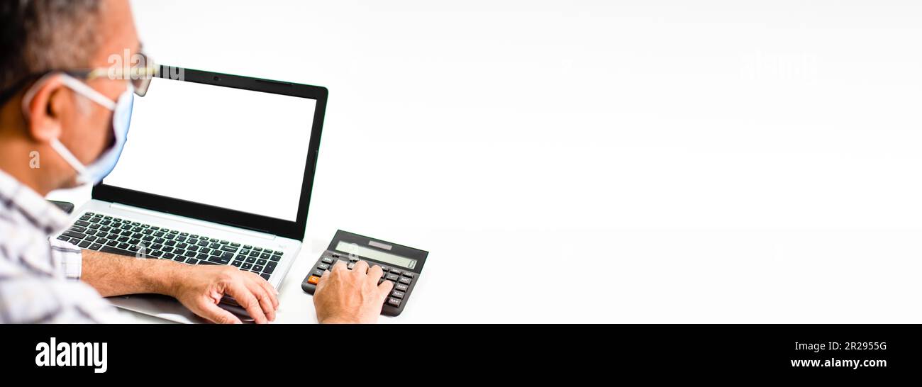 Nahaufnahme des Fingers eines Mannes, der einen Taschenrechner auf einen weißen Tisch in einem Büro drückt, um die Bankzinsen zu berechnen. Der leere und weiße Bildschirm des Laptops. Kopien Stockfoto