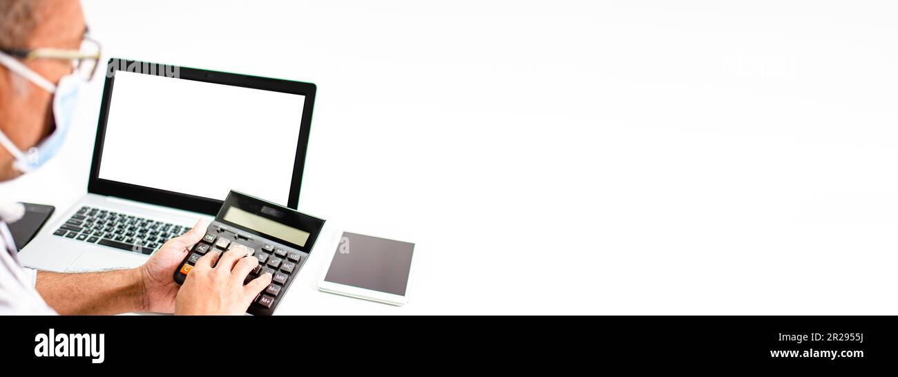 Nahaufnahme eines Fingers, der einen Taschenrechner auf einen weißen Tisch in einem Büro drückt, um die Zinsen für Kunden zu berechnen, die einen Kredit benötigen, den Laptop Stockfoto