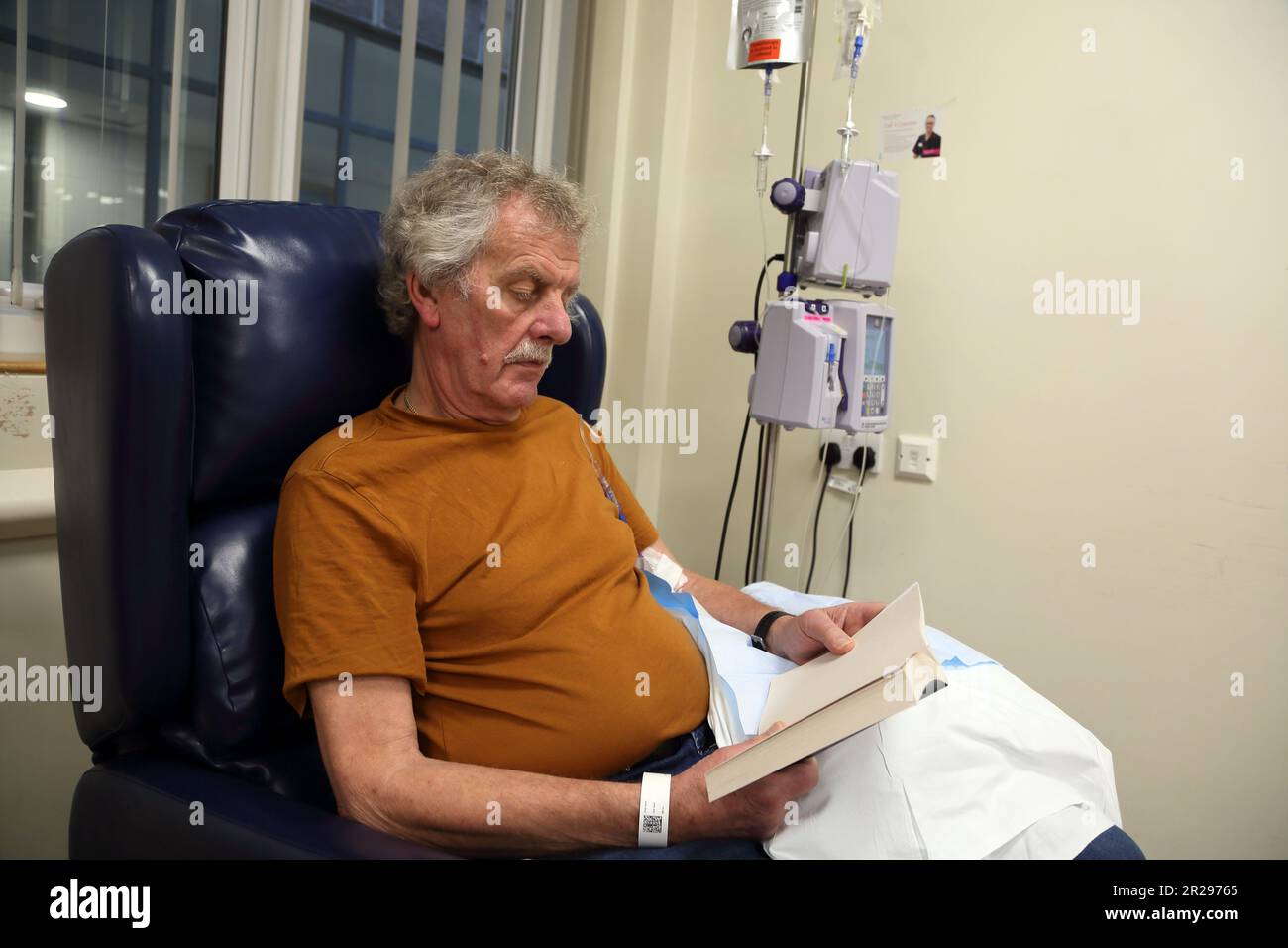 Lesebuch von Krebspatienten während einer Chemotherapie mit intravenöser Infusions-Chemotherapie Pump Surrey England Stockfoto