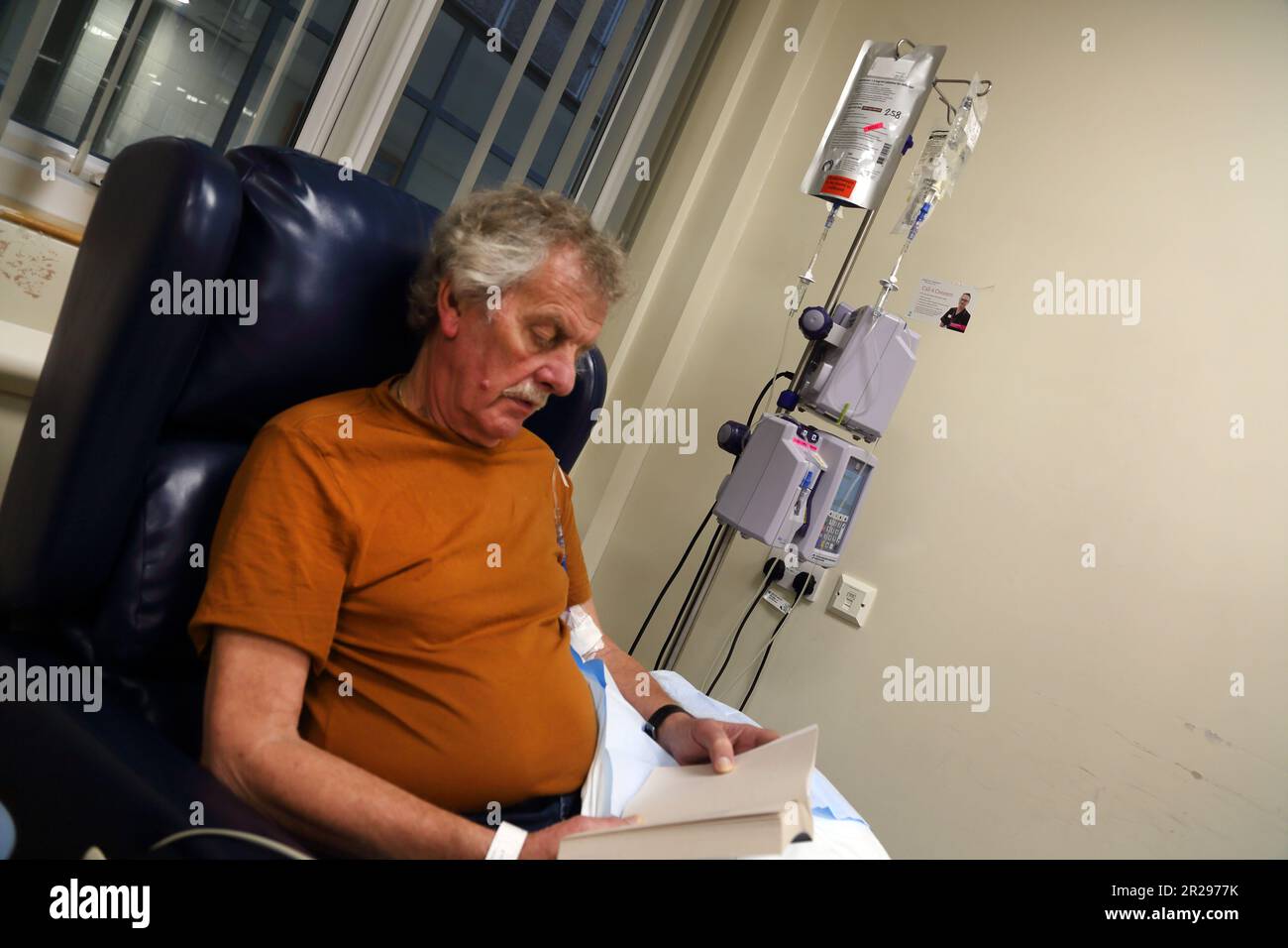 Lesebuch von Krebspatienten während einer Chemotherapie mit intravenöser Infusions-Chemotherapie Pump Surrey England Stockfoto