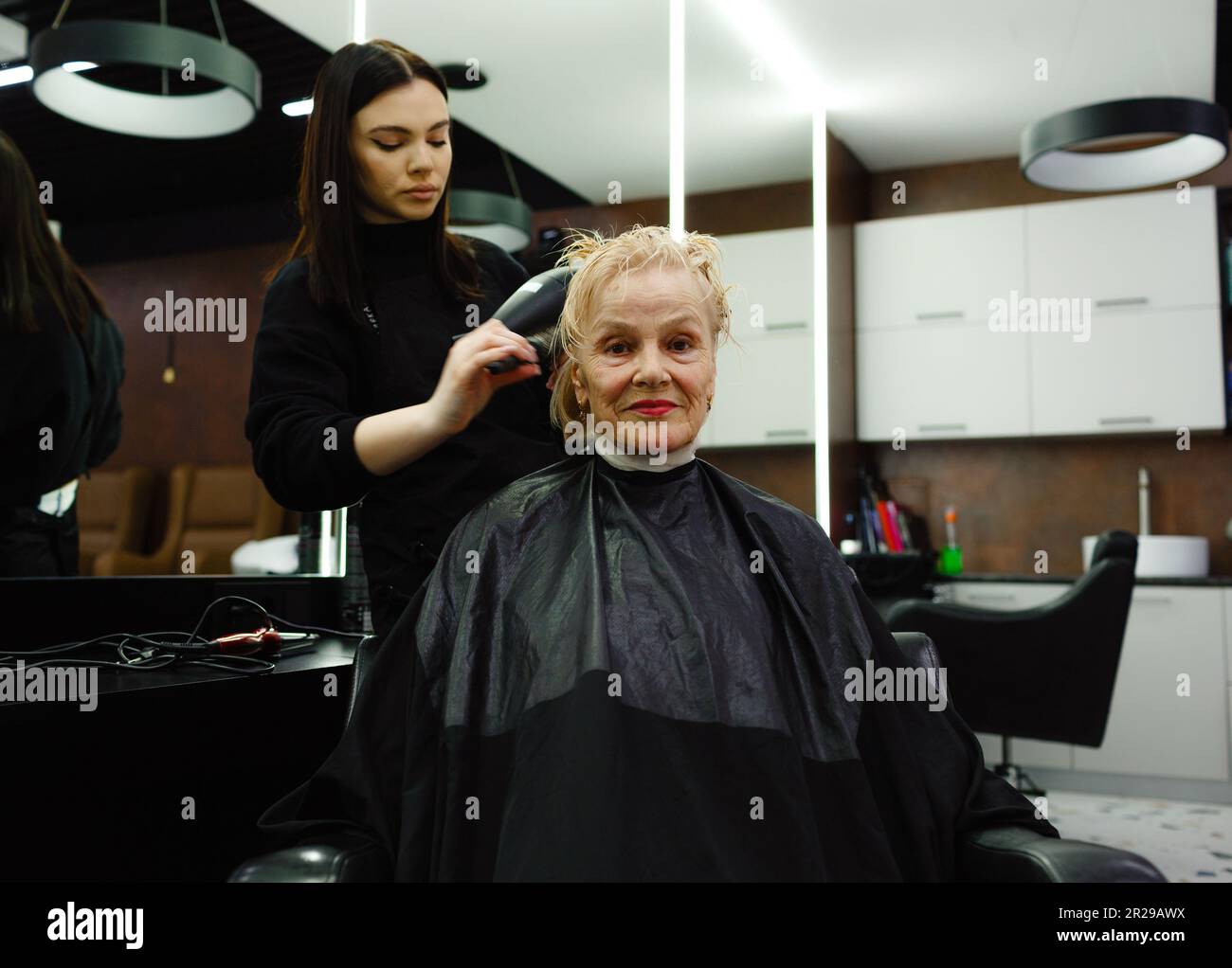 Porträt einer älteren Frau beim Friseur. Ein erfahrener Friseur stylen die Haare für einen Kunden Stockfoto