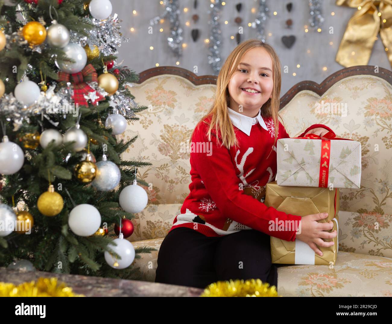 Glückliches Mädchen mit Weihnachtsgeschenken und Weihnachtsbaum im Hintergrund Stockfoto