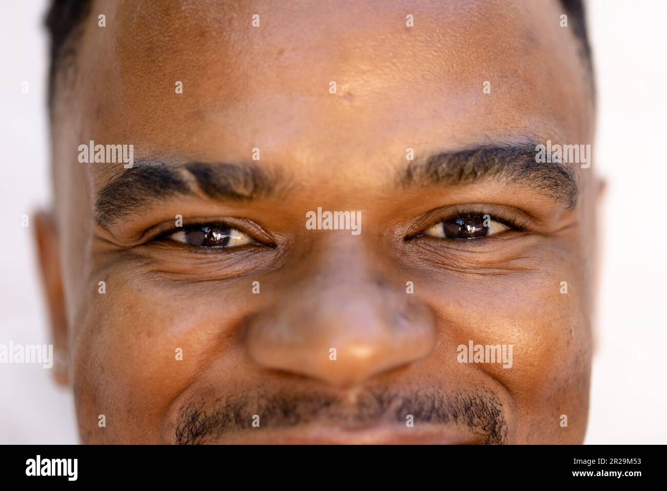 Nahaufnahme eines jungen afroamerikanischen Mannes mit schwarzen, lächelnden und selbstbewussten Augen Stockfoto