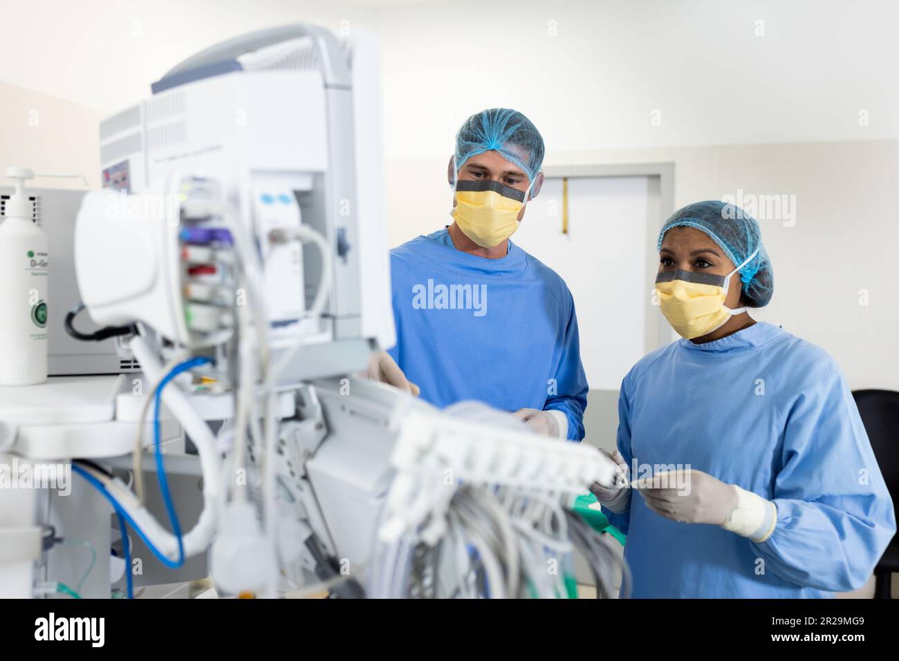 Diverse weibliche und männliche Chirurgen, die technische Ausrüstung im Operationssaal, Kopierraum studieren Stockfoto