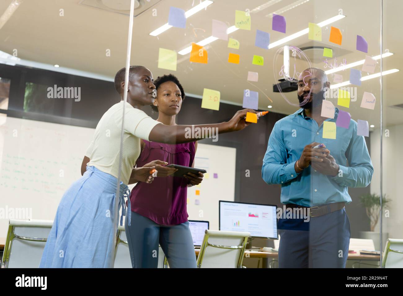 afroamerikanische Kollegen schreiben auf Glaswand und diskutieren über Haftnotizen im Büro Stockfoto