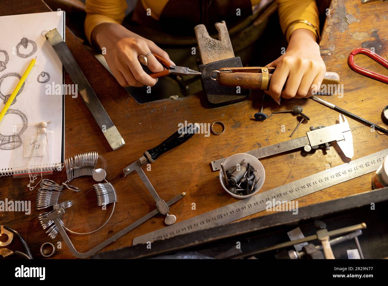 Mittelschicht einer Kaukasierin, die Schmuck mit Werkzeugen in der Schmuckwerkstatt herstellt Stockfoto