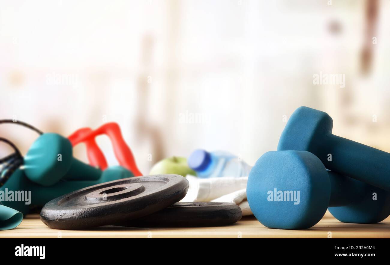 Sportausrüstung auf einem Holztisch mit Kurzhanteln und Gewichtsplatten. Vorderansicht. Stockfoto