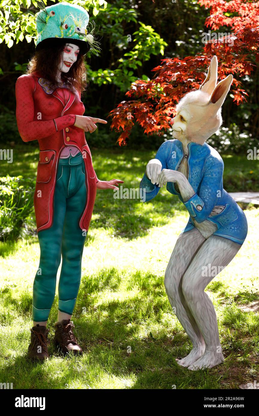 GEEK ART - Bodypainting and Transformaking: Alice im Wunderland fotografiert mit Julia als verrückter Hutmacher und Janina als Weißer Hase im Czarnecki Garden. Hamelin am 18. Mai 2023 - Ein Projekt des Fotografen Tschiponnique Skupin und Bodypainter Enrico Lein Stockfoto