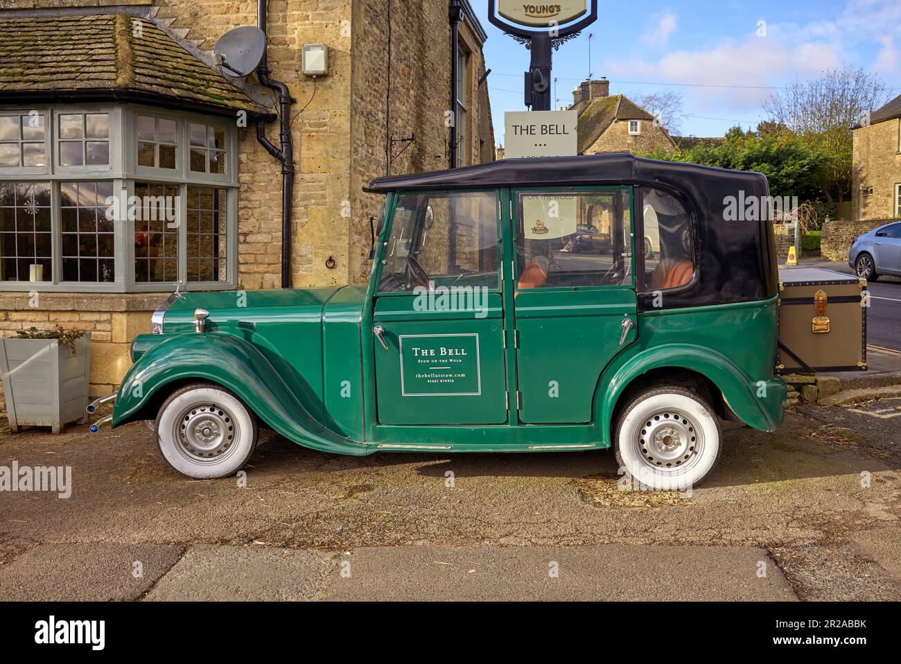 Das Bell Hotel mit dem Suzhou Eagle EG6060K Elektroauto, das einem alten Rolls Royce ähnelt. Stow-on-the-Wold, Cotswolds, Gloucestershire, England Stockfoto