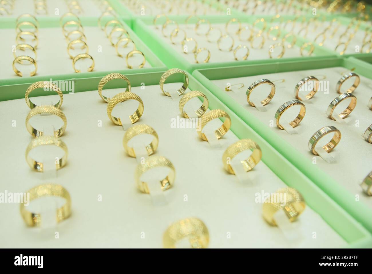 Goldene Schmuck-Verlobungsringe, goldene Diamantringe werden im Schaufenster des Einzelhandelsgeschäfts gezeigt. Schmuck zeigt Konzeptfoto-Idee. Selektiver Fokus. Stockfoto