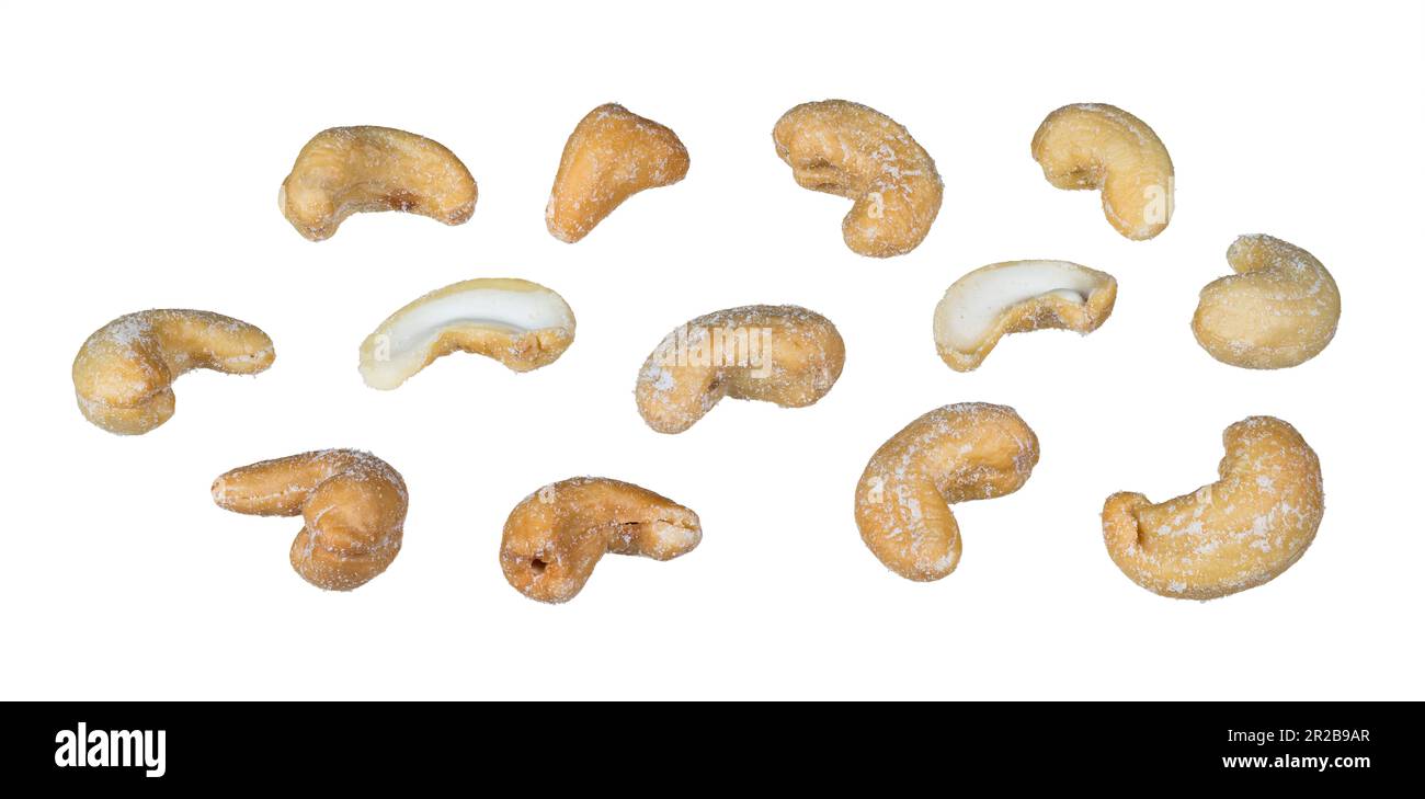 Ganze oder halbierte salzige Kaschu-Nüsse, isoliert auf weißem Hintergrund. Anacardium occidentale. Schließen Sie eine Gruppe köstlicher gerösteter Cashews mit Salz. Stockfoto