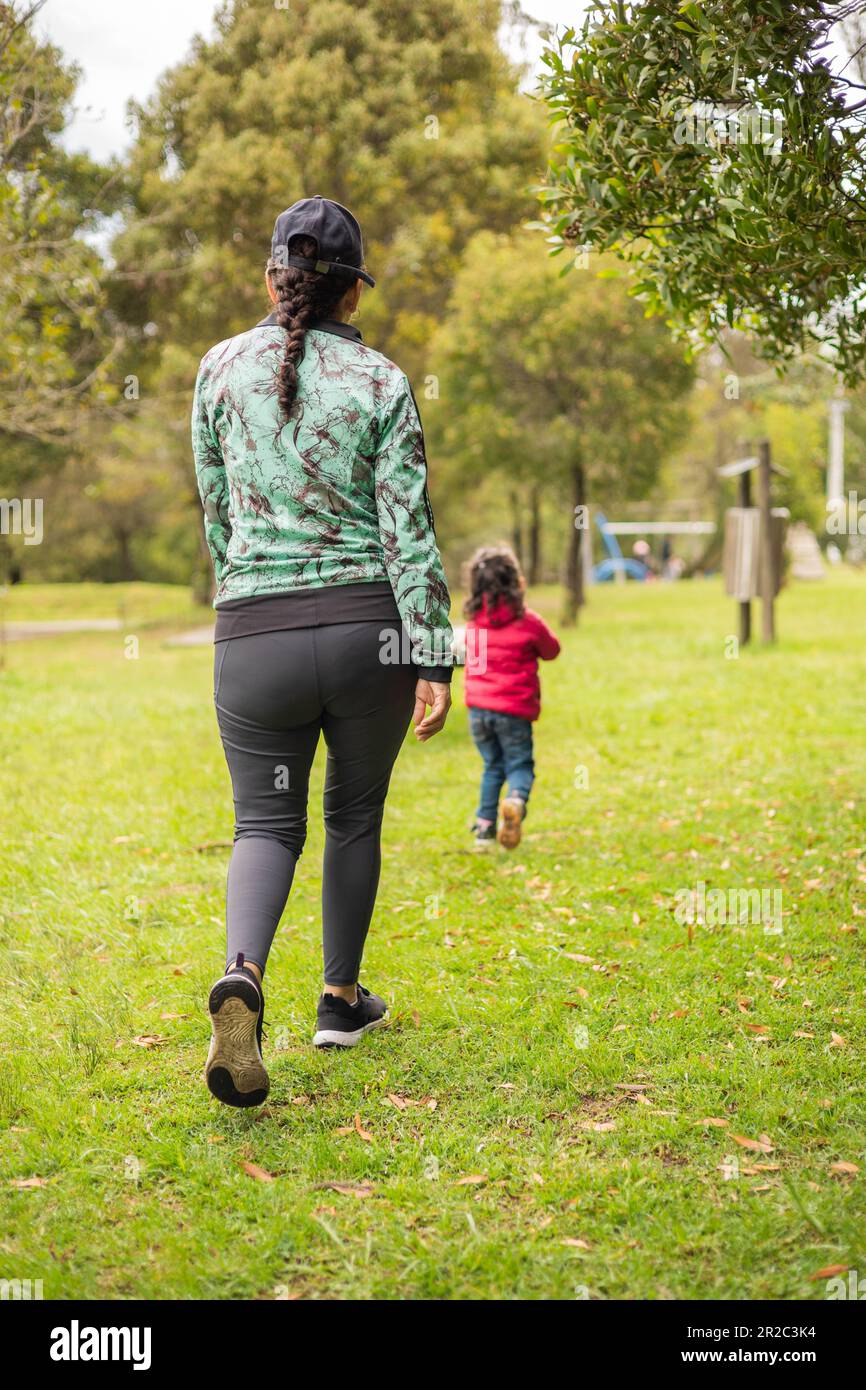Sie gehen mit ihrer Tochter spazieren, leben am Ruhetag im Park, umgeben von der Natur, die Liebe zur Familie, die Spaß im Freien hat, tragen Sportkleidung Stockfoto